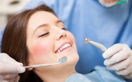 Smiling-Young-Woman-in-Dentists-chair-dentists-gloved-hand-holding-dental-tool.-e1461903556112